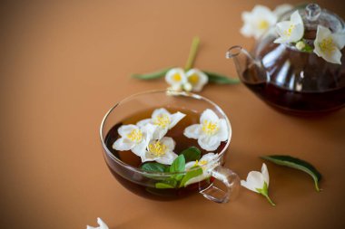 Kahverengi arka planda, cam kaplamalı yasemin çayı..