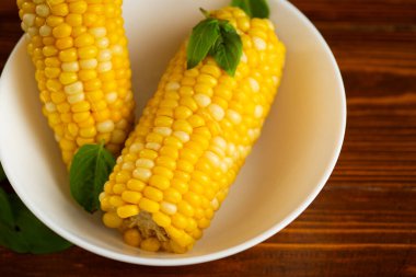 Beyaz bir tabakta iki tane haşlanmış mısır..