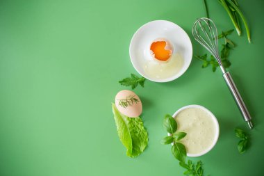 Yeşil arka planda bir kasede otlu ev yapımı mayonez..