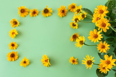Parlak sarı çiçekler yeşil arkaplanda güzel bir şekilde dizilmiş..