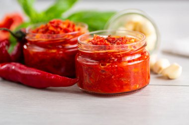 Sarımsaklı cam kavanozlarda ev yapımı kırmızı biber ezmesi..