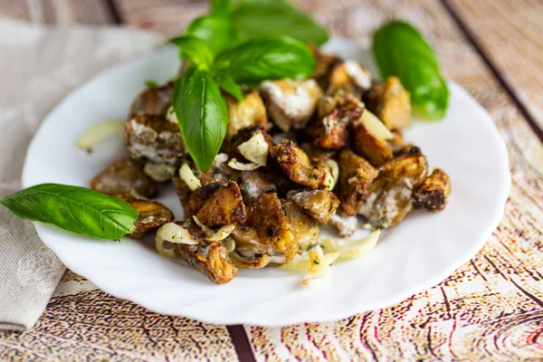 Appetizing eggplant pieces with sauce and fresh basil leaves.