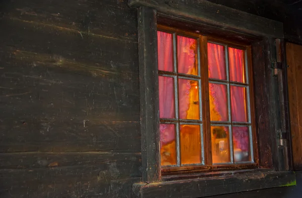 Ambiance chaleureuse derrière la fenêtre avec des barres vitrées d'une cabane en rondins Image En Vente