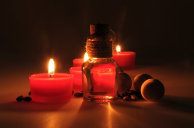 spa kompozisyonu. kokulu mumlar, kahve çekirdekleri, aromatik ahşap topları ve bir stoper ile cam sürahi yağ. Fotoğraf karanlık bir anahtarla yürütülür. kısmen renkli fotoğraf.