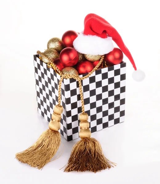 Caja de regalo en estilo dominó, llena de bolas de Navidad. Sombreros Santa Claus.Decoración hecha de cordones de oro con borlas . — Foto de Stock