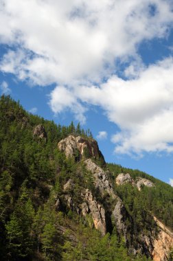 Mavi gökyüzü ve kümülüs bulutlar üzerinde Doğu Sayan Dağları ve Mount Munku-Sardyk. Kısmen renkli fotoğraf.
