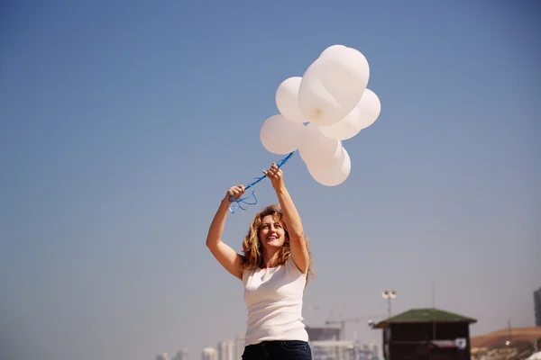 Kvinna anläggning vita ballonger — Stockfoto