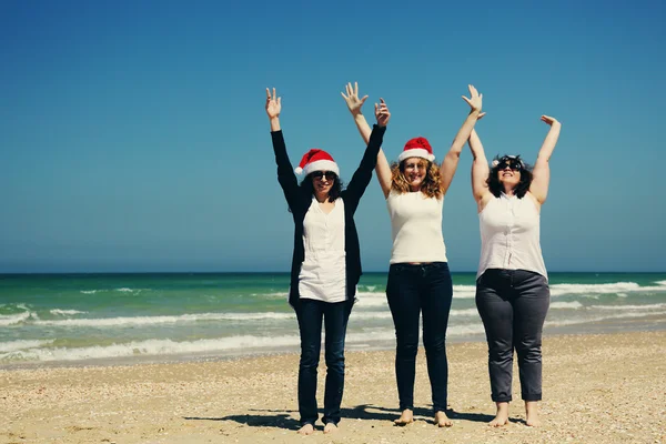 Mujeres en sombreros de Navidad en la playa —  Fotos de Stock