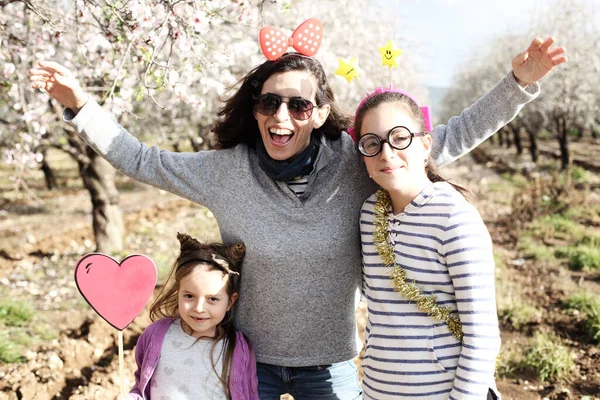 Mom and two daughters have fun in carnival costumes outdoors