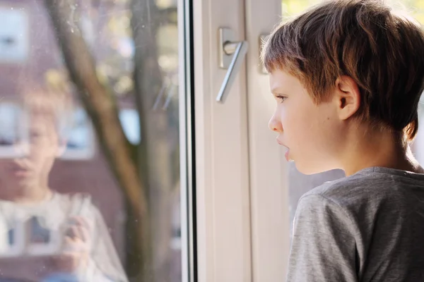 Boy looking through the window — Stock Photo, Image