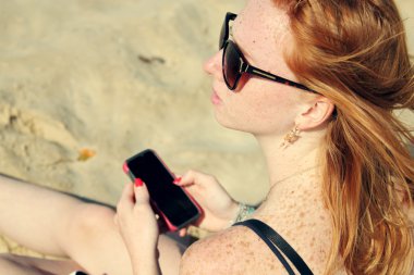 Akıllı telefon tutan genç bir kadın.