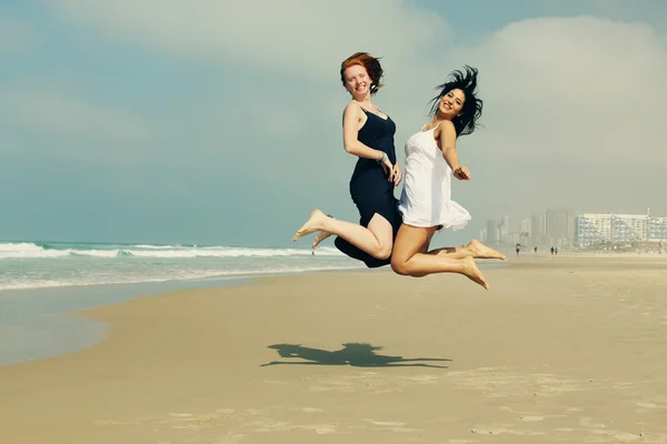Girlfriends jumping at the beach — Stock Photo, Image
