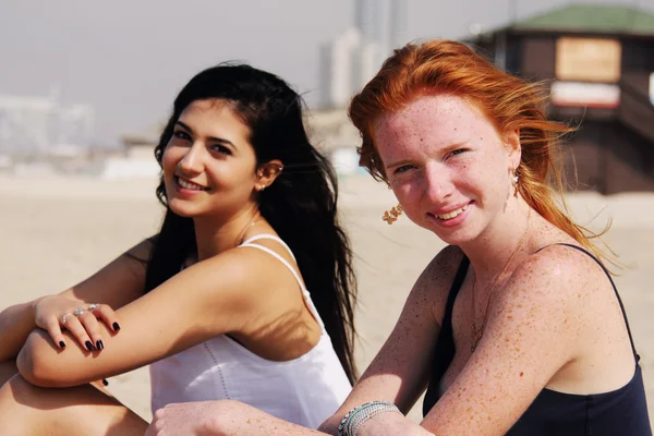 Flickvänner sitter på stranden — Stockfoto