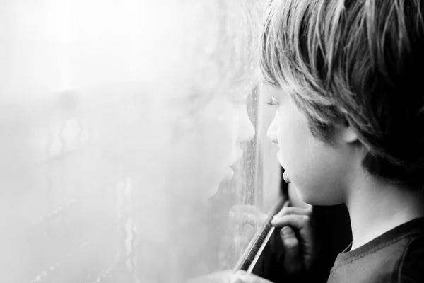 Boy looking through window — Stock Photo, Image