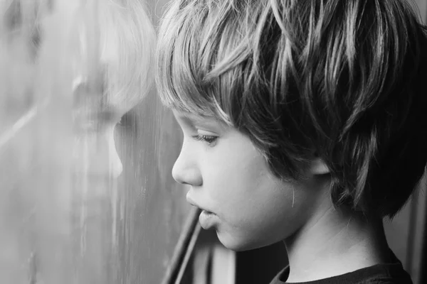 Jongen op zoek via venster — Stockfoto