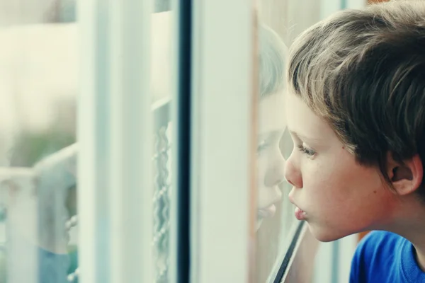 Boy looking through the window — Stock Photo, Image