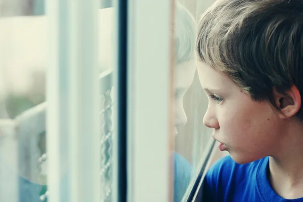 Boy looking through the window — Stock Photo, Image