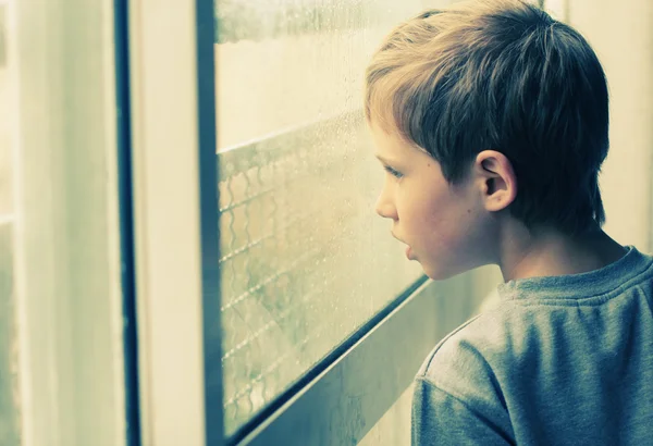 Little boy looking through window — Stock Photo, Image