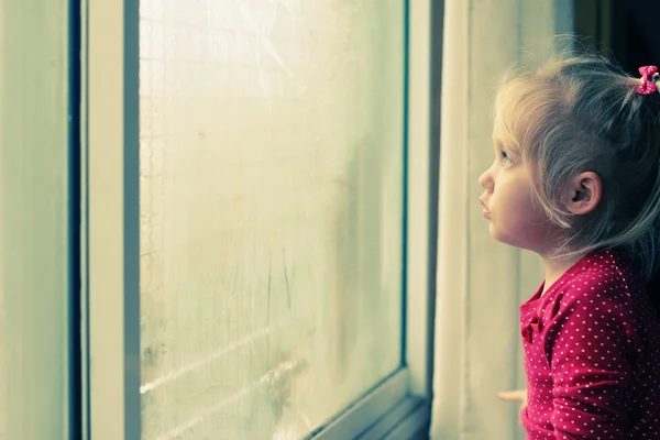 Petite fille regardant par la fenêtre — Photo