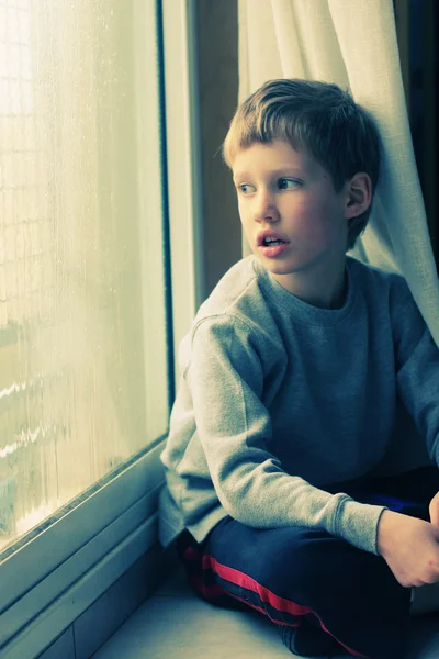 Маленький мальчик смотрит в окно — стоковое фото