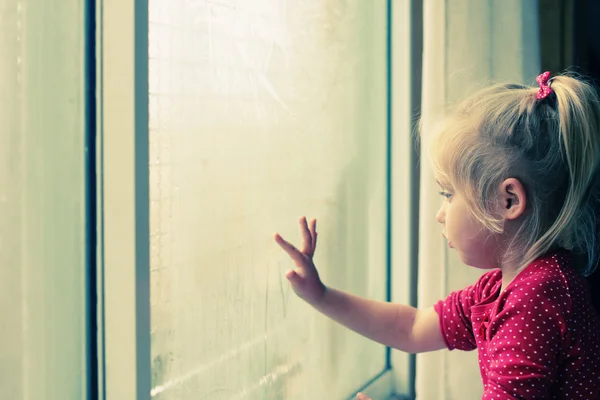Маленькая девочка смотрит в окно — стоковое фото