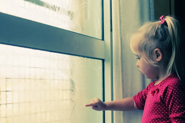 Ragazzina che guarda attraverso la finestra — Foto Stock