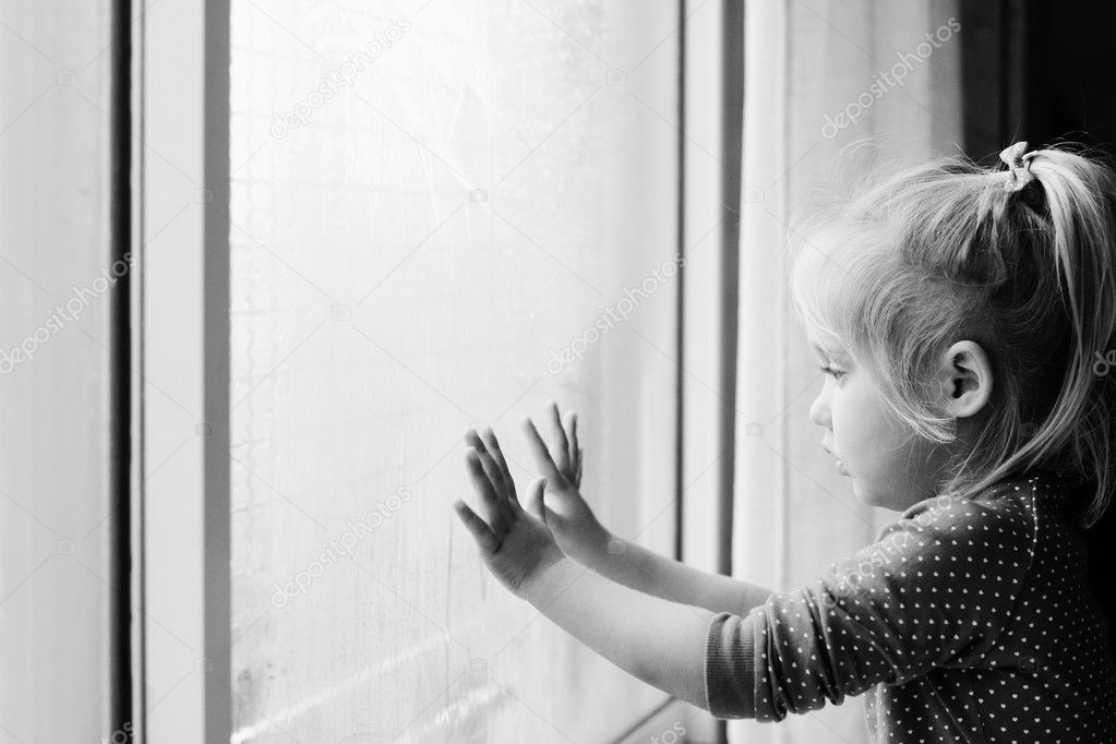 Little girl looking through window