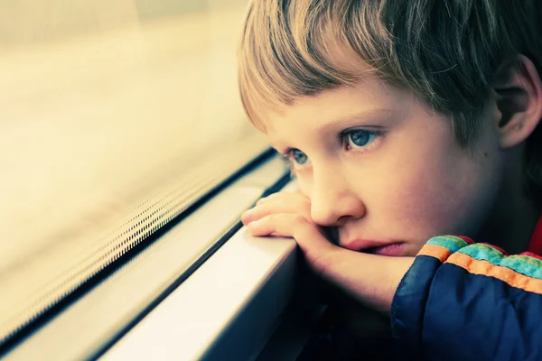 Jongen op zoek via venster — Stockfoto