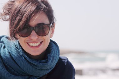 Sahilde güneş gözlüklü bir kadın.