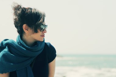 Sahilde güneş gözlüklü bir kadın.