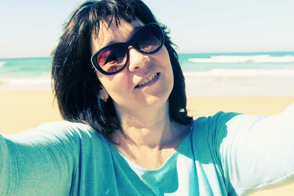 Volwassen vrouw maken selfie op strand — Stockfoto