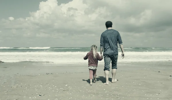 Baba ve kızı sahilde yürüyor. — Stok fotoğraf