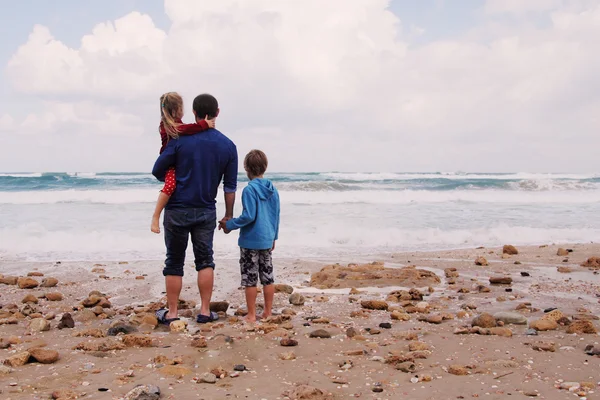 Far, son och dotter promenerar på stranden — Stockfoto