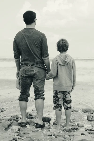 Far och son promenader på stranden — Stockfoto