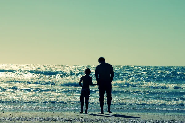 Far och son promenader på stranden — Stockfoto