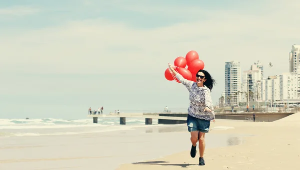 Kvinna anläggning röda ballonger — Stockfoto