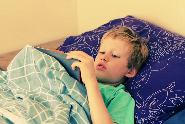 Мальчик лежит в постели и играет — стоковое фото