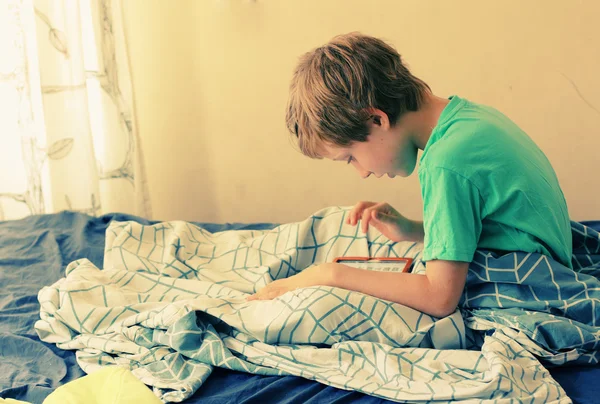 Menino está na cama e brinca — Fotografia de Stock