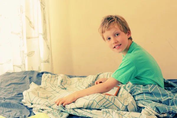 Boy lies in bed and plays — Stock Photo, Image