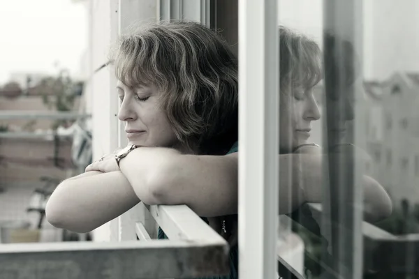 Frau steht am Fenster — Stockfoto