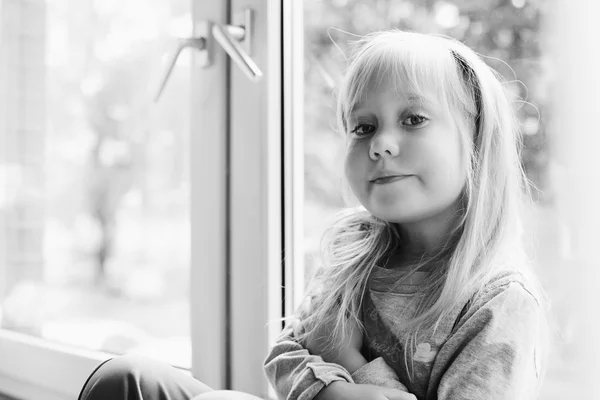 Klein meisje zitten in de buurt van venster — Stockfoto