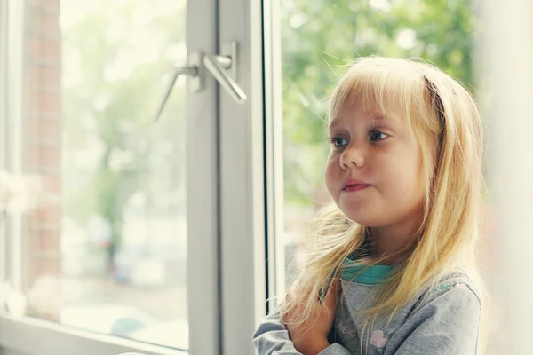 Kleines Mädchen sitzt am Fenster — Stockfoto