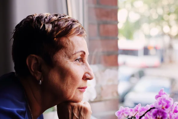 Frau schaut zum Fenster — Stockfoto