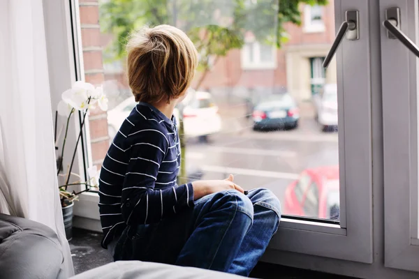 Маленький мальчик сидит у окна — стоковое фото