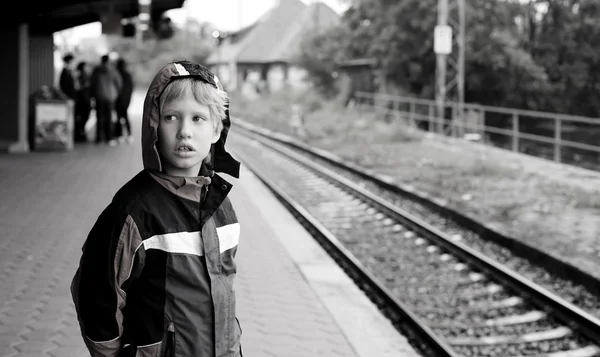 Маленький мальчик стоит на железнодорожной станции — стоковое фото