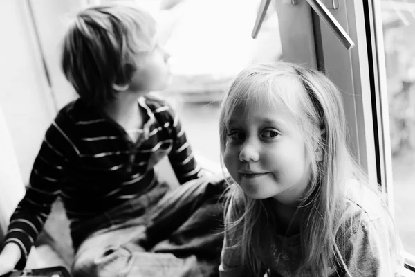 Syster och bror sitter nära fönster — Stockfoto