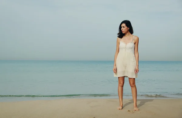 女人站在岸边的沙滩上 — 图库照片