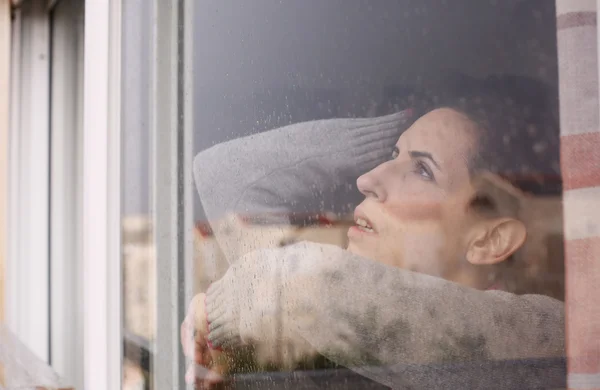 Woman looking through the window — Stock Photo, Image