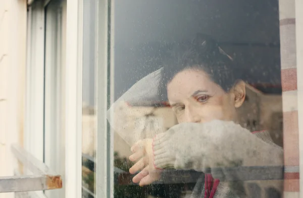 Žena při pohledu přes okno — Stock fotografie