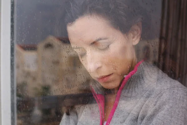 Vrouw op zoek door het raam — Stockfoto